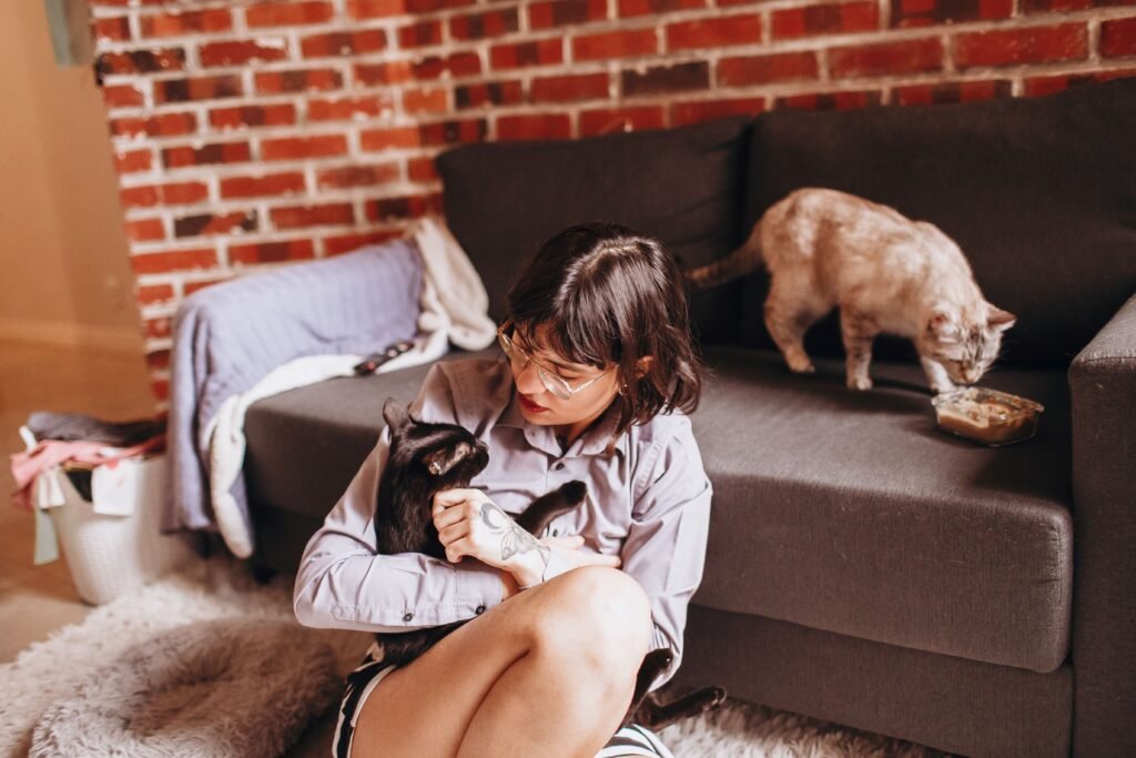 Woman sitting on the floor lovingly cuddling a black cat