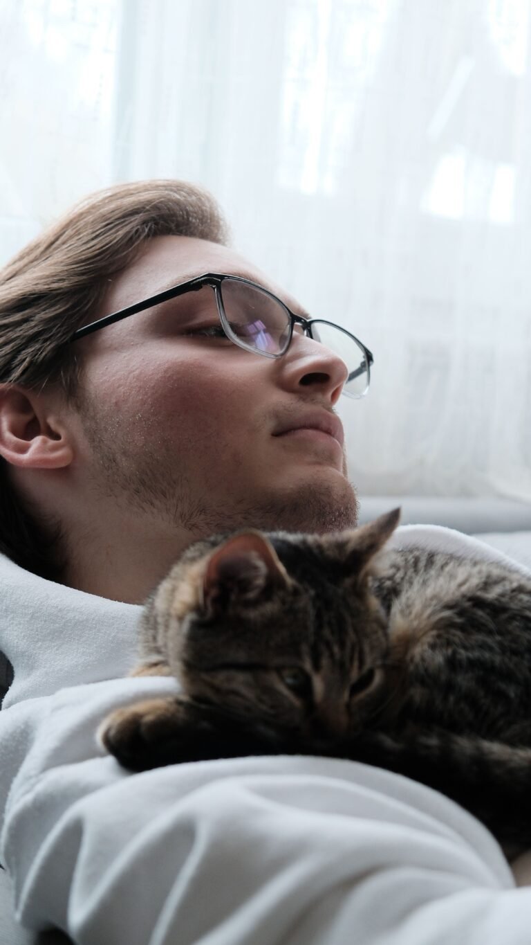 Young man relaxing indoors with a tabby cat on his chest