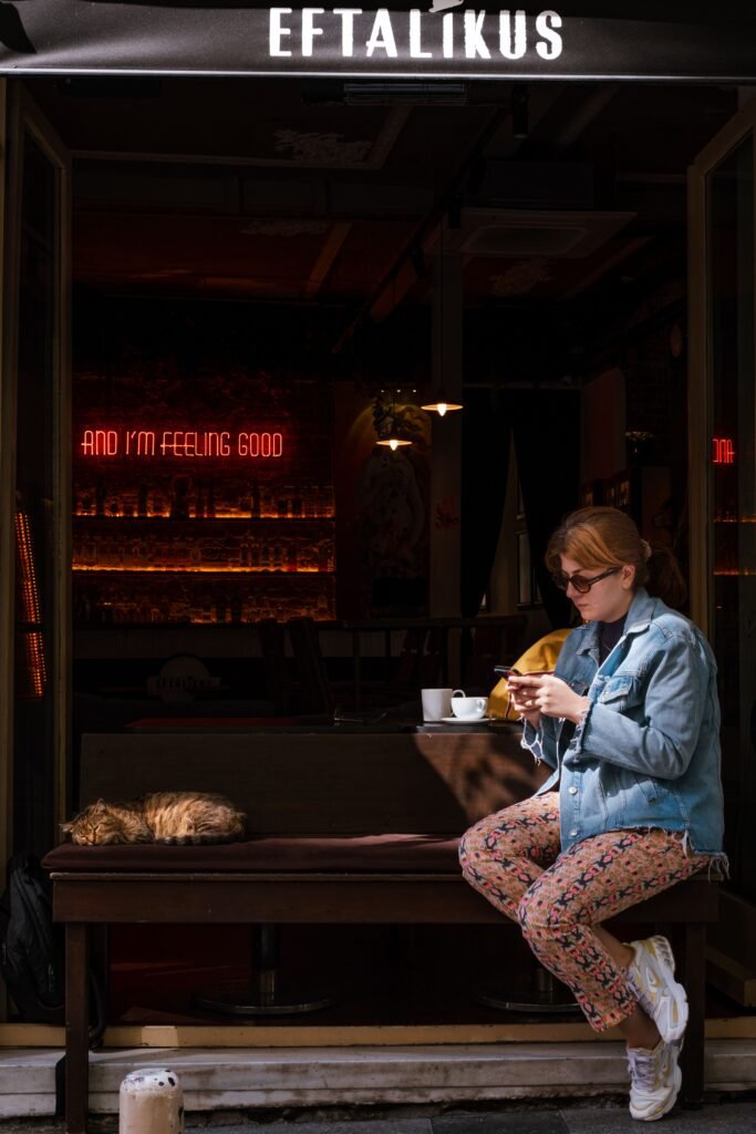 Woman relaxing at a cafe with a cat beside her